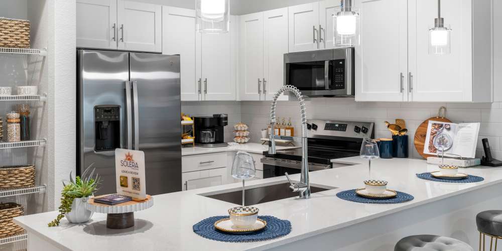 Modern kitchen with stainless steel appliances, granite countertops, and pendant lights over a spacious island at Solera at Avalon Trails in Delray Beach, Florida