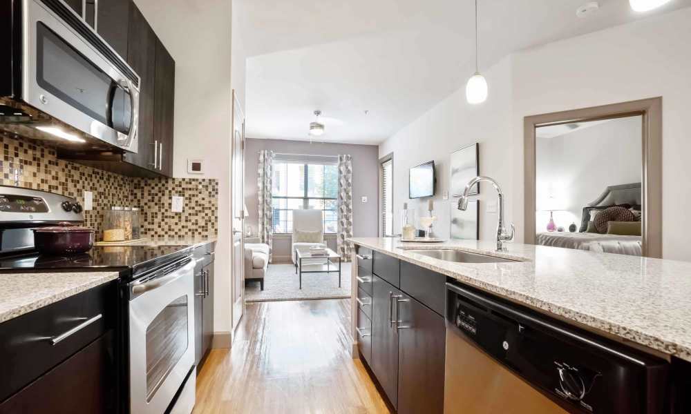 Apartment kitchen with wood-style flooring and dark cabinetry at Grapevine Station in Grapevine,Texas