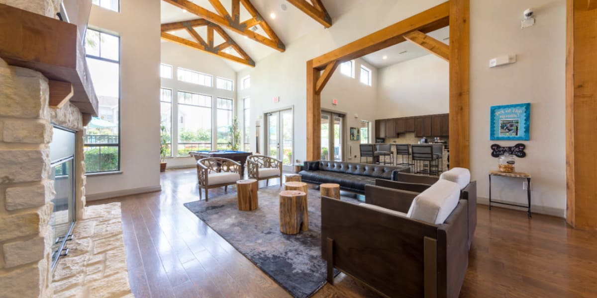 Community clubhouse sitting area with stone fireplace overlooking dining area at Marquis at Sugar Land in Sugar Land, Texas