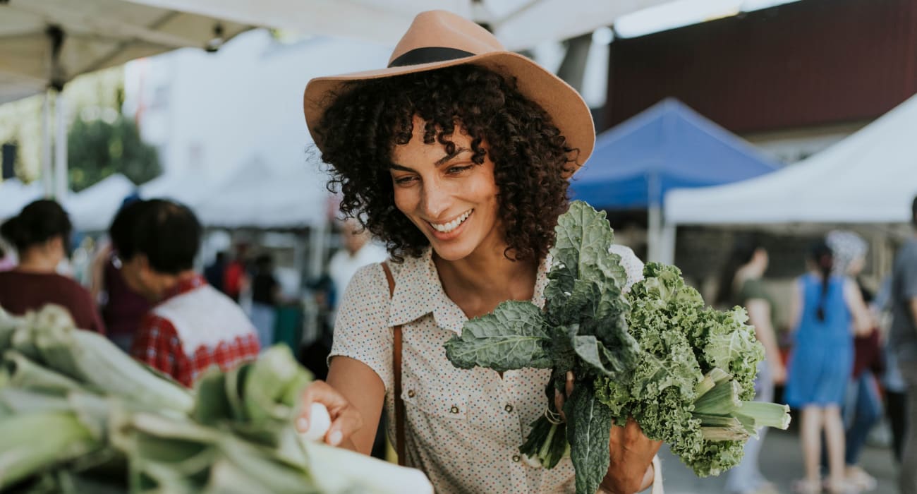 Woman out at the local outdoor market picking up some kale in Little Falls, New Jersey near Park Lane Apartments