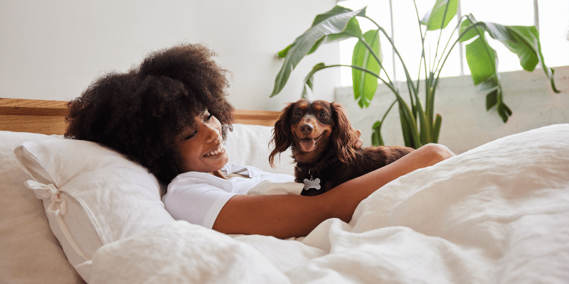 A smiling resident with her dog in bed at Serra Mesa in Oceanside, California
