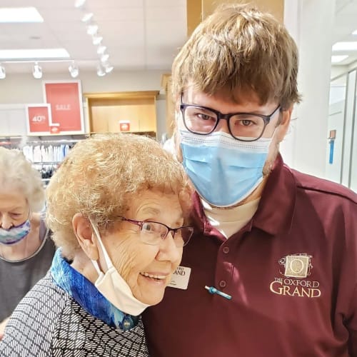 Happy resident hugging a masked caretaker at The Oxford Grand Assisted Living & Memory Care in Wichita, Kansas