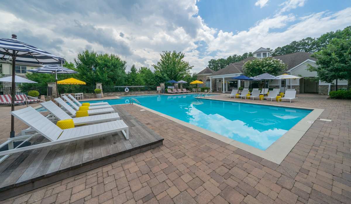 Resort-style pool with lounge chairs, umbrellas, and vibrant landscaping in a welcoming community setting at Belmont Place Apartments in Marietta, Georgia