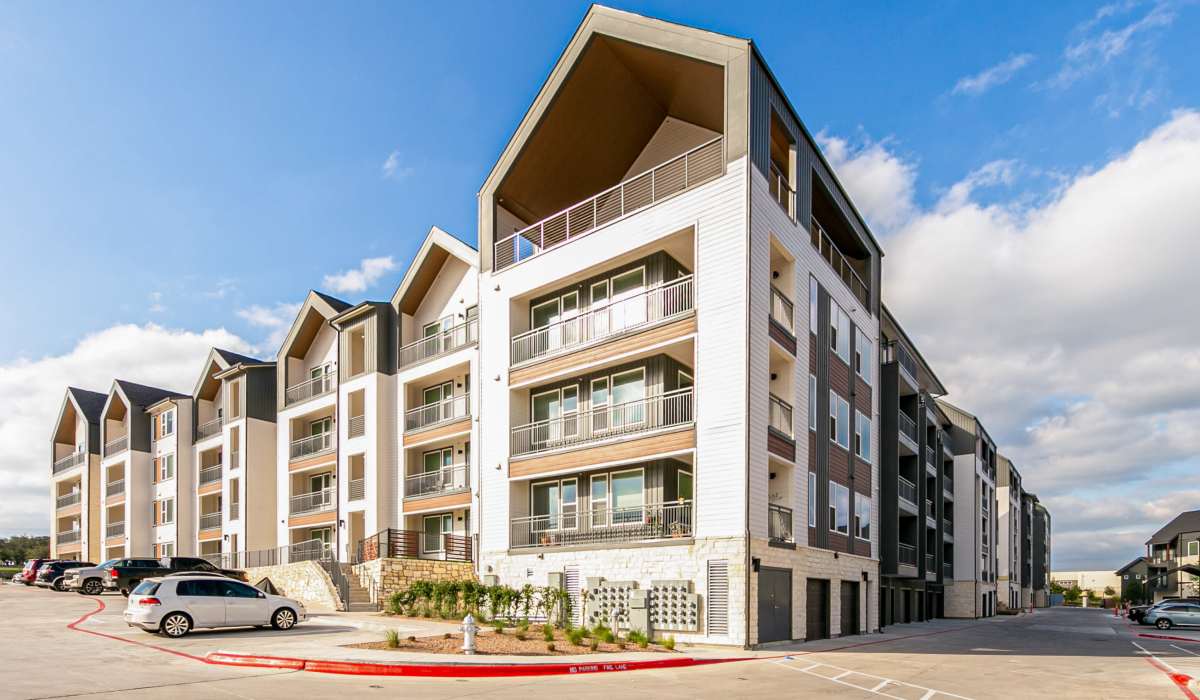 Scenic exterior view of a lively community with cars parked in-front at The View at Belterra in Austin, Texas