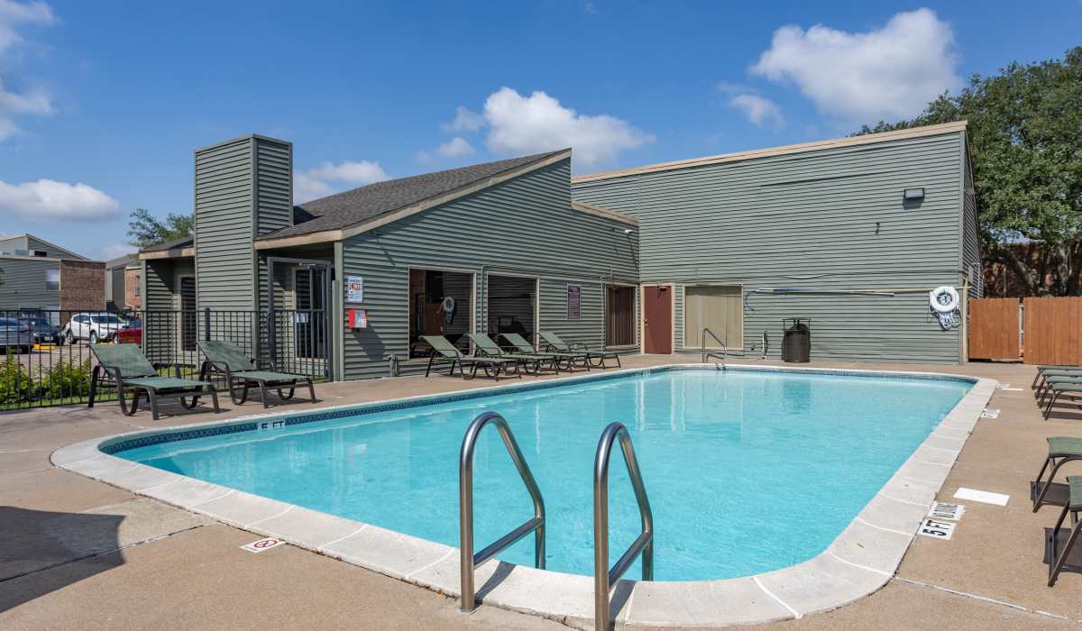 Swimming pool with lounge chairs at University Green Apartments in Houston, Texas