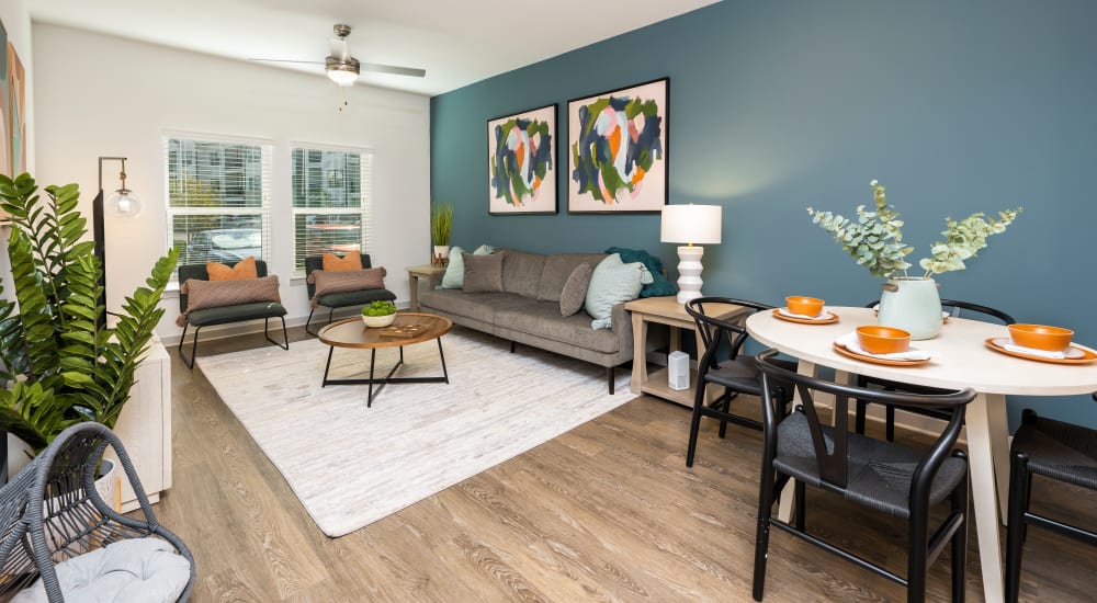 A spacious living room with wood flooring and ceiling fan in a model home at Novo Kendall Town in Jacksonville, Florida