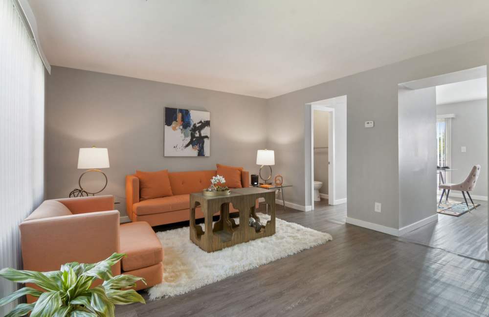 Bright living room with orange furniture, wood-style flooring, and modern decor accents at Fairway Ridge in Baltimore, Maryland