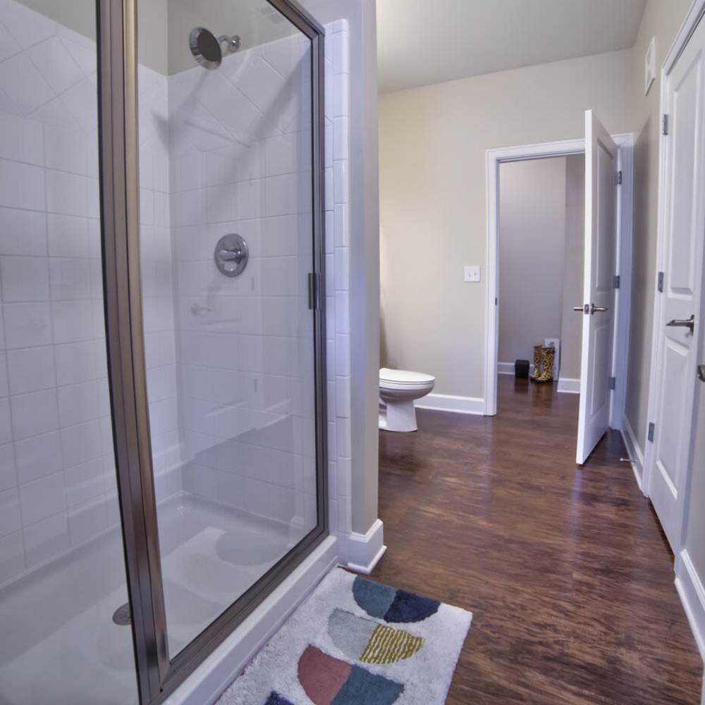 Stylish bathroom featuring a modern shower and elegant, rich wood flooring at Avonlea Square in Smyrna, Georgia.