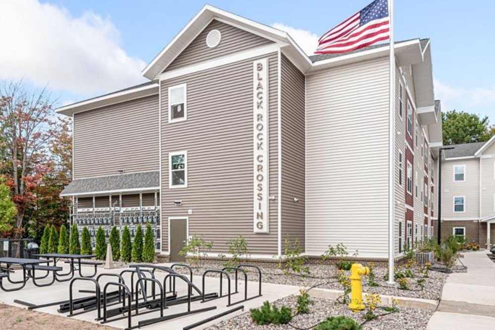 Modern apartment community with bike racks, landscaped gardens, and a welcoming entrance at Black Rock Crossing in Marquette, Michigan