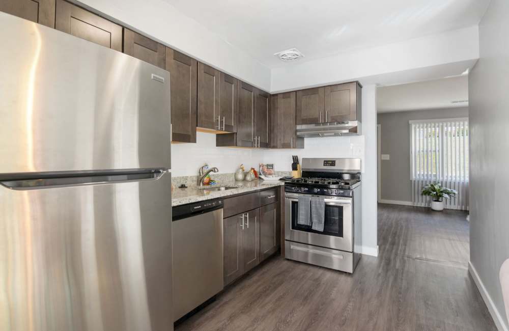 Modern kitchen with stainless steel appliances, granite countertops, and wood-style flooring at Fairway Ridge in Baltimore, Maryland