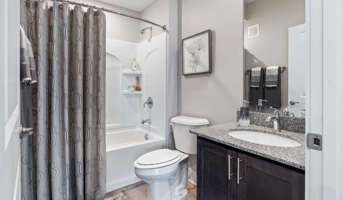 Modern bathroom with granite countertops and tub at Gentry East Apartments in Cincinnati, Ohio
