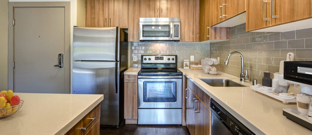 A kitchen with quartz countertops and stainless steel appliances at Harborside Marina Bay Apartments in Marina del Rey, California