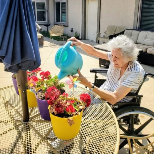 A Resident watering some flowers outside at Glen Carr House Memory Care in Derby, Kansas