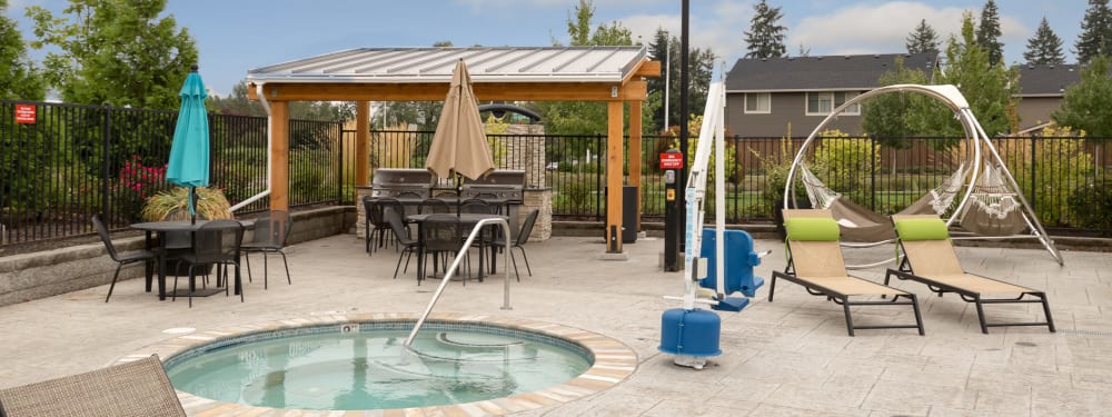 Hot tub, BBQ pit, tables, and cozy landscaping at Terrene at the Grove in Wilsonville, Oregon