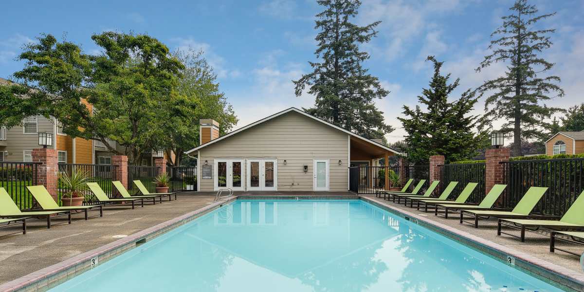 Beautiful resort-style swimming pool with a lush backdrop at Carriage Park Apartments in Vancouver, Washington