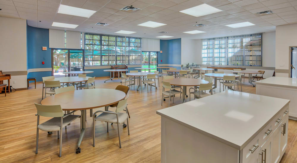 Community room with shuffleboard, a piano, and tables for games and dining at The Springs in La Mesa, California