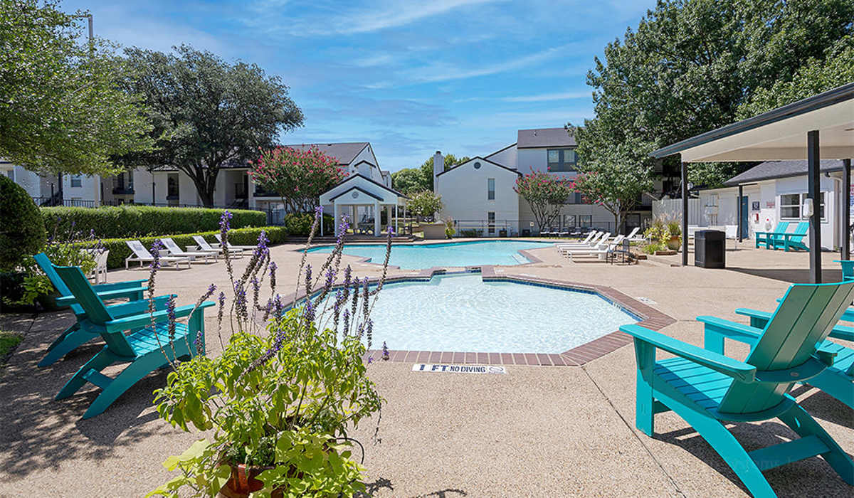 Swimming pool with pool side chairs at Oaks at Duck Creek in Garland, Texas