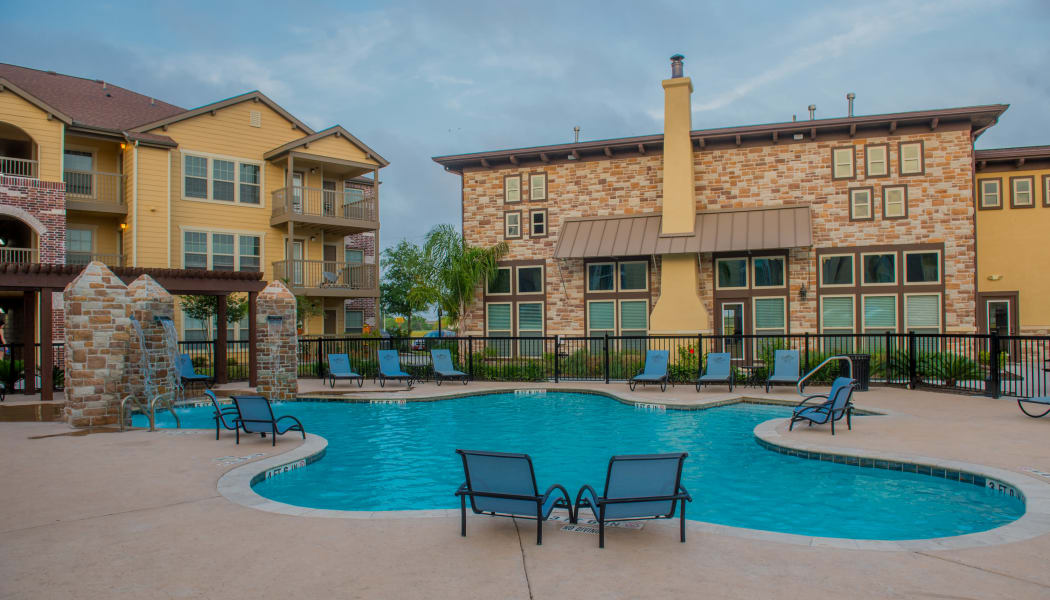 Sparkling swimming pool with poolside seating at Tuscana Bay Apartments in Corpus Christi, Texas