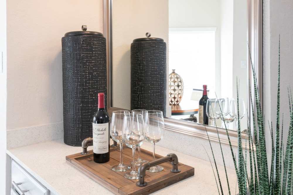 Counter in the living room with wine glasses and a bottle of red wine, with a mirror in the background at Copper Chase in Arlington, Texas