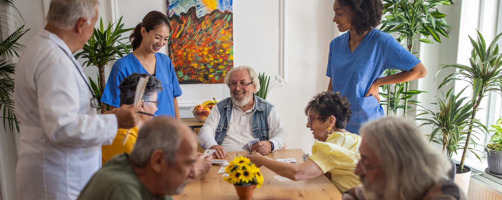 Resident and staff playing cards and laughing  at Vista Prairie Communities in Champlin, Minnesota