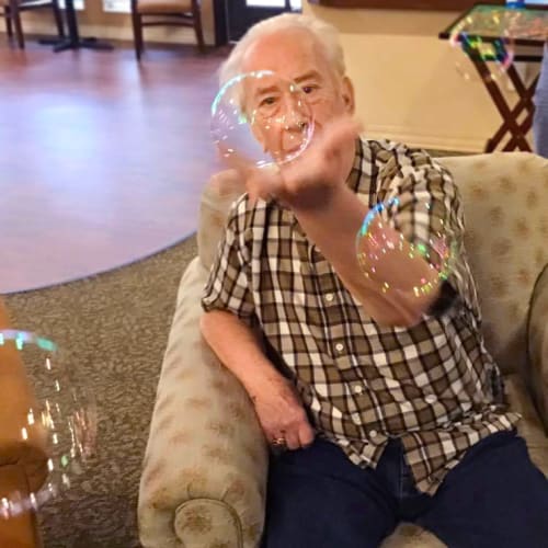 Resident playing with bubbles at Oxford Glen Memory Care at Grand Prairie in Grand Prairie, Texas