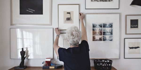 Resident hanging a framed picture on her apartment wall at a WISH community