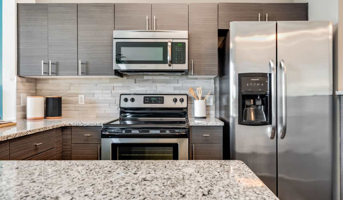 Open kitchen with stainless-steel appliances, storage spaces and granite countertop at San Marco in Boca Raton, Florida