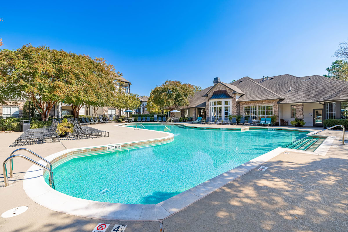 Enclosed pool area with lounge chairs, umbrellas, and BBQs at Marquis at Carmel Commons in Charlotte, North Carolina