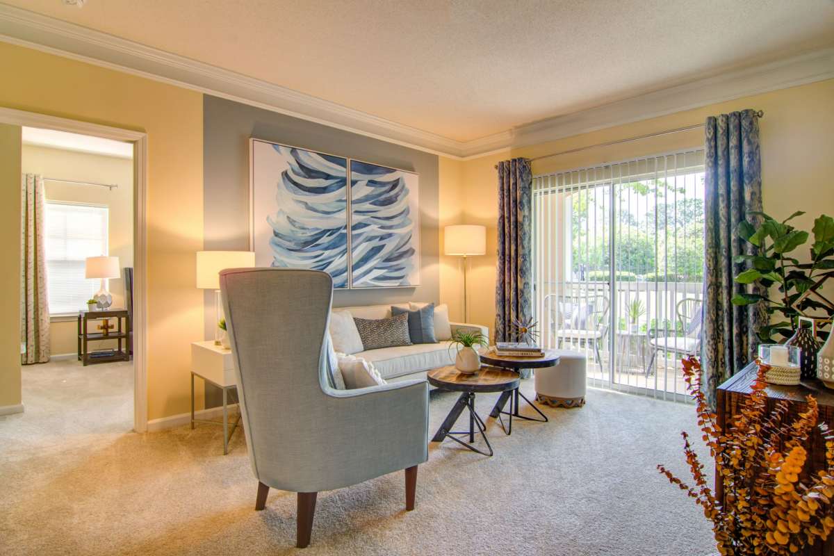 Living room with carpet and access to balcony at Alta Mill Apartments, Austell, Georgia