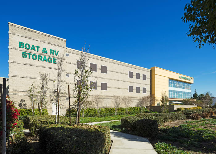 Outdoor storage units with green doors and wide driveways at A Storage Place in Montclair, California