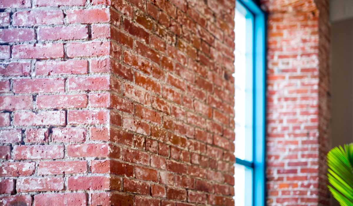 Garden style exposed brick wall with a blue window at Commonwealth Landing Lofts in Fall River, Massachusetts