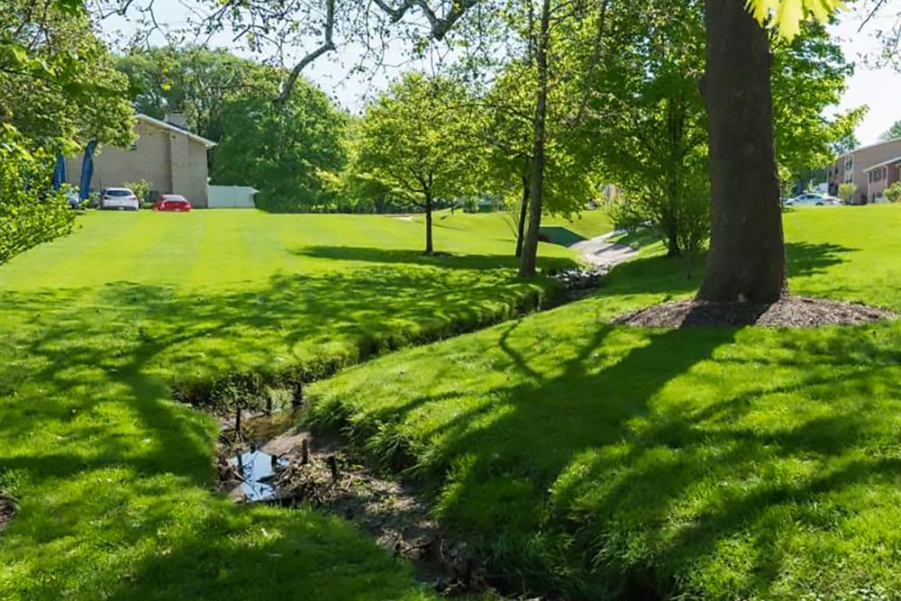 Creek and green lawn at Hampton Manor Apartments and Townhomes in Cockeysville, Maryland