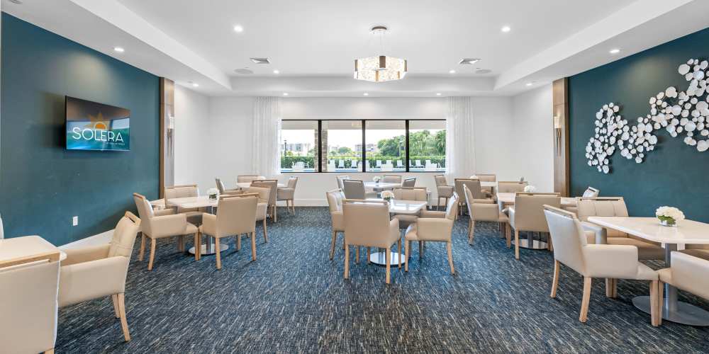 Bright dining area with modern furniture, large windows, and decorative wall art at Solera at Avalon Trails in Delray Beach, Florida