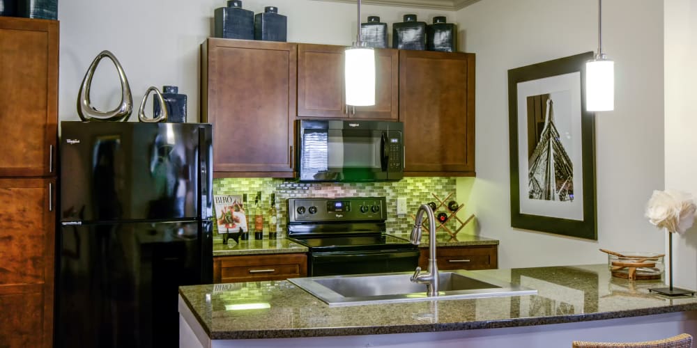 Granite countertop kitchen with bar seating at Firewheel Apartments in San Antonio