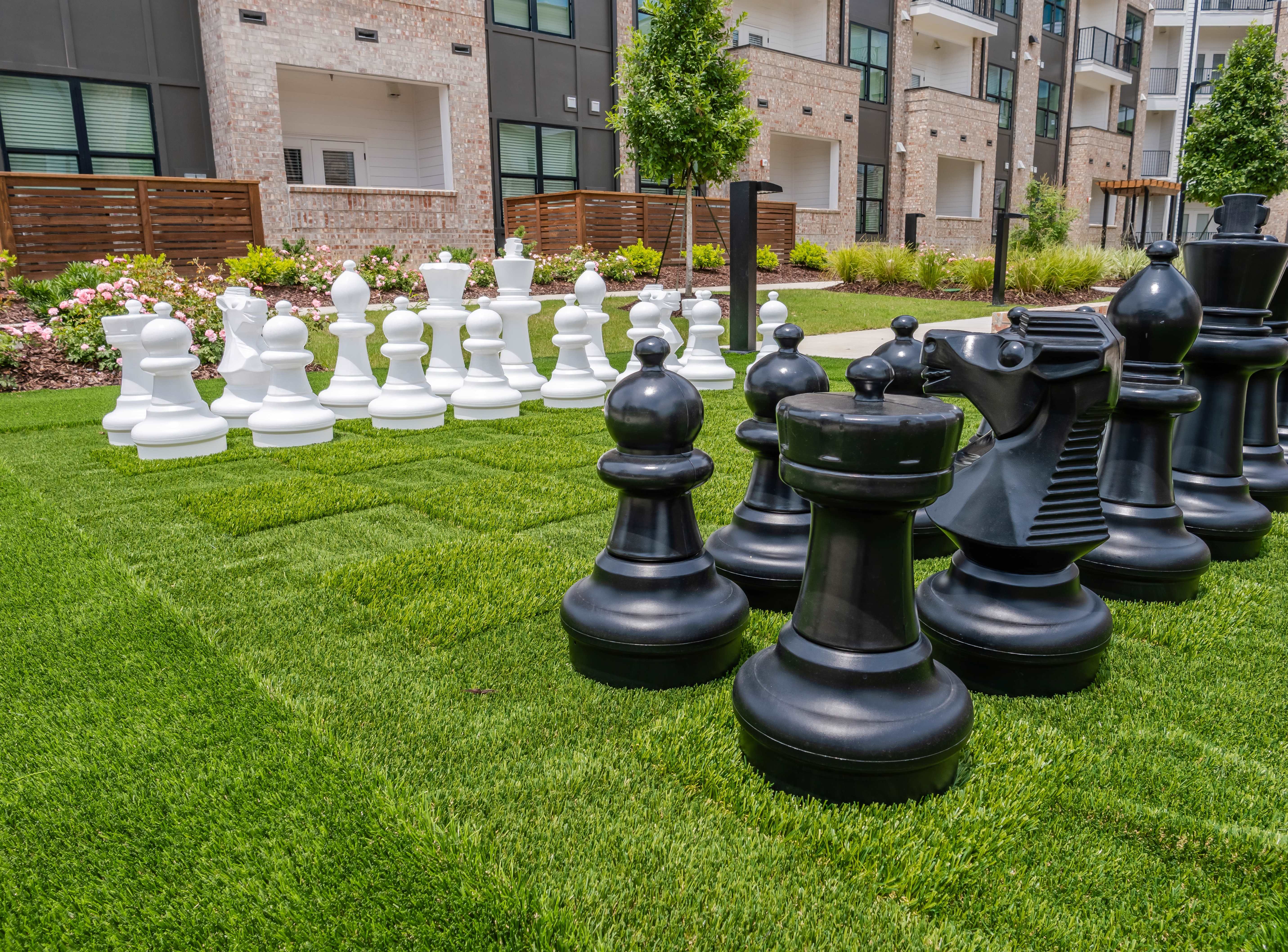 giant chess game in outdoor social courtyard included in amenities pictured in front of modern and clean apartment buildings exterior photo with charcoal grey concrete finishes and exposed brick style appearing edgy and trendy for baton rouge new apartment homes  Map + Directions | The Heights at Picardy in Baton Rouge, Louisiana