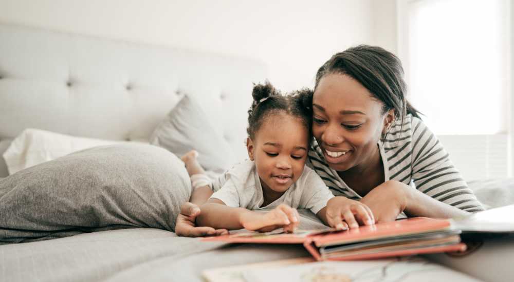 mom and child reading on a bed at 51st and King Apartments in Chicago, Illinois
