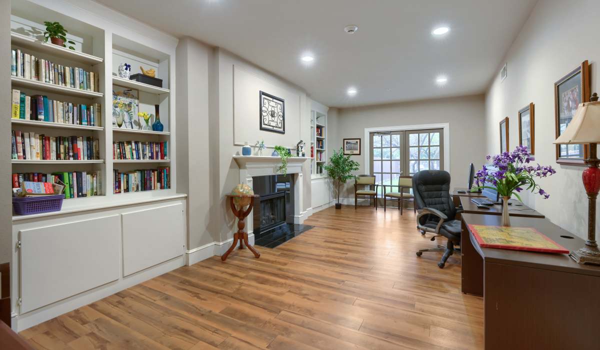 Spacious living area with wood-style flooring, built-in bookshelves, and a cozy fireplace at Lindbergh Parc Senior Apartments in Fort Worth, Texas
