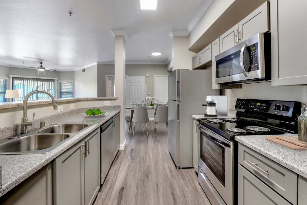 Well-designed kitchen with stainless-steel appliances and a view of cozy dining space in the apartment at Avion Apartments in Rancho Cordova, California