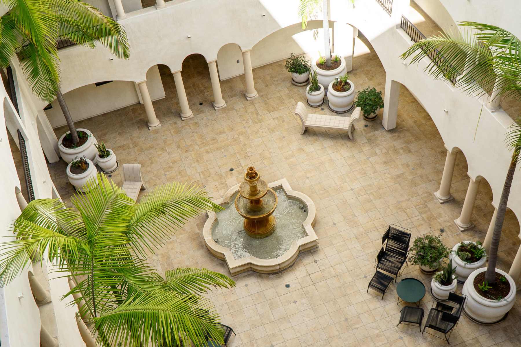 Open-air courtyard with water fountain, palm trees at Luxe Villas in Brentwood, California