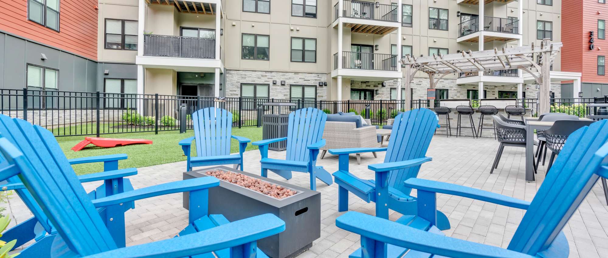 Blue adirondack chairs around a fire pit at Latitude at South Portland in Portland, Maine