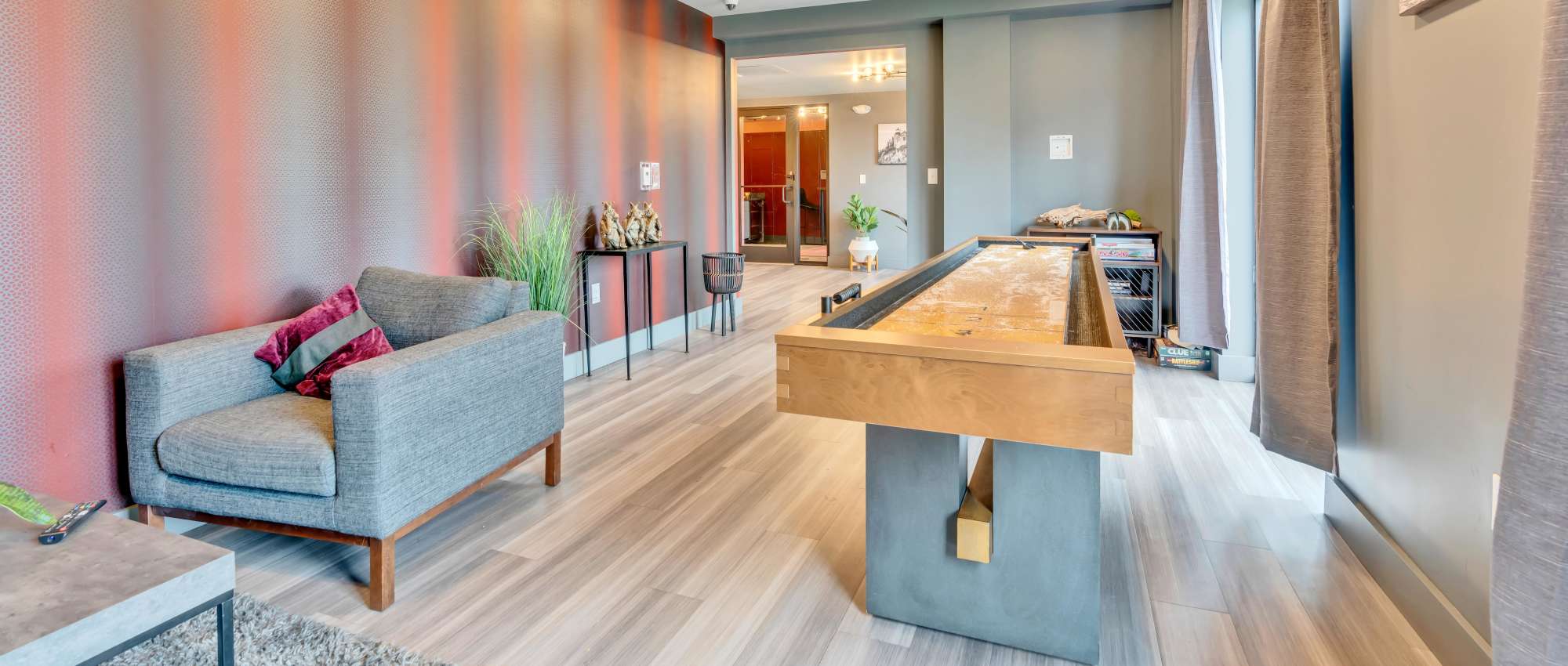 Gray sofa with purple pillows and shuffleboard at Latitude at South Portland in Portland, Maine