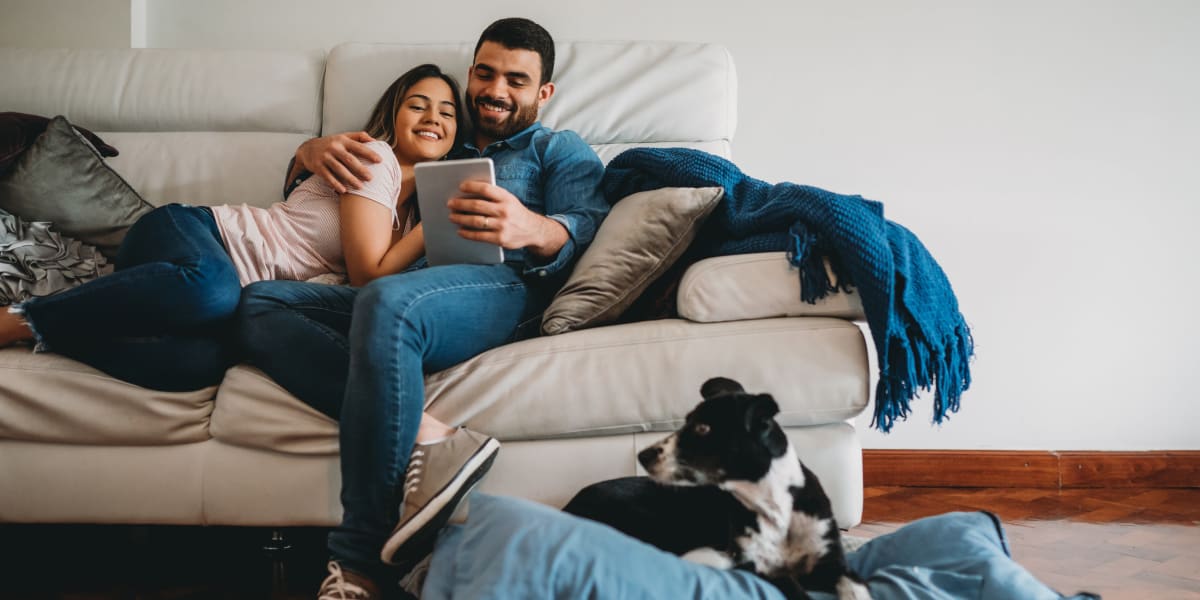 Young couple resting on couch with dog nearby at Marquis at Ladera Vista in Austin, Texas