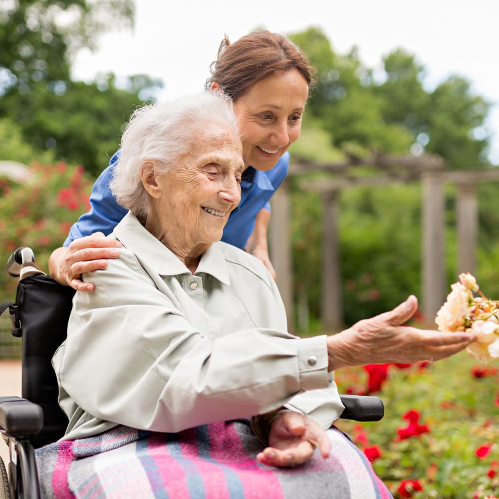 Senior picking flowers with nurse at Almond Heights in Orangevale, California