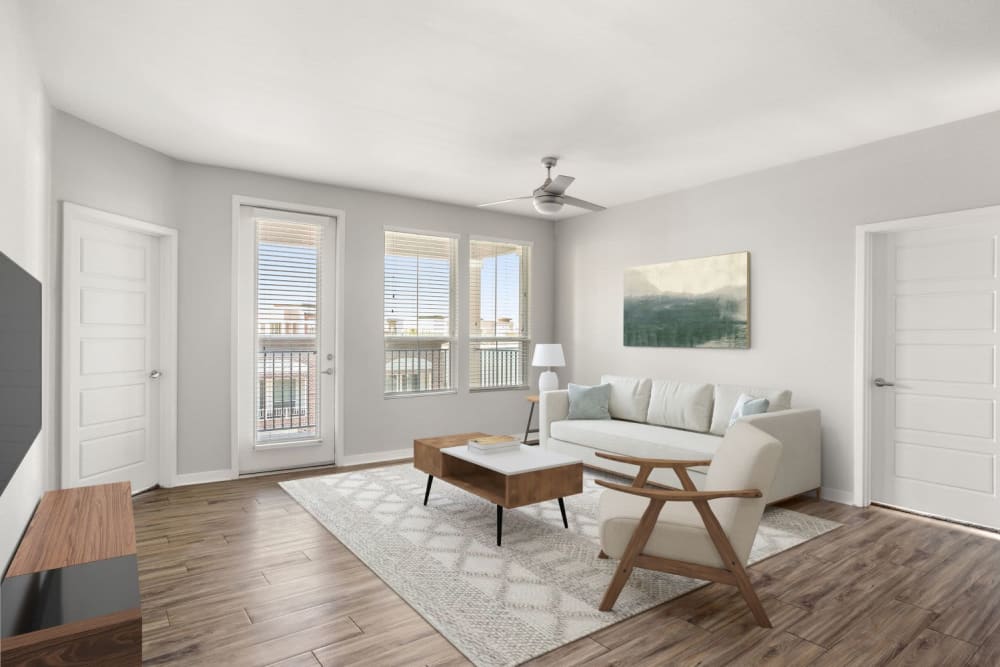 Model living room with vinyl plank flooring and a ceiling fan opening onto a private balcony at Town Commons in Gilbert, Arizona