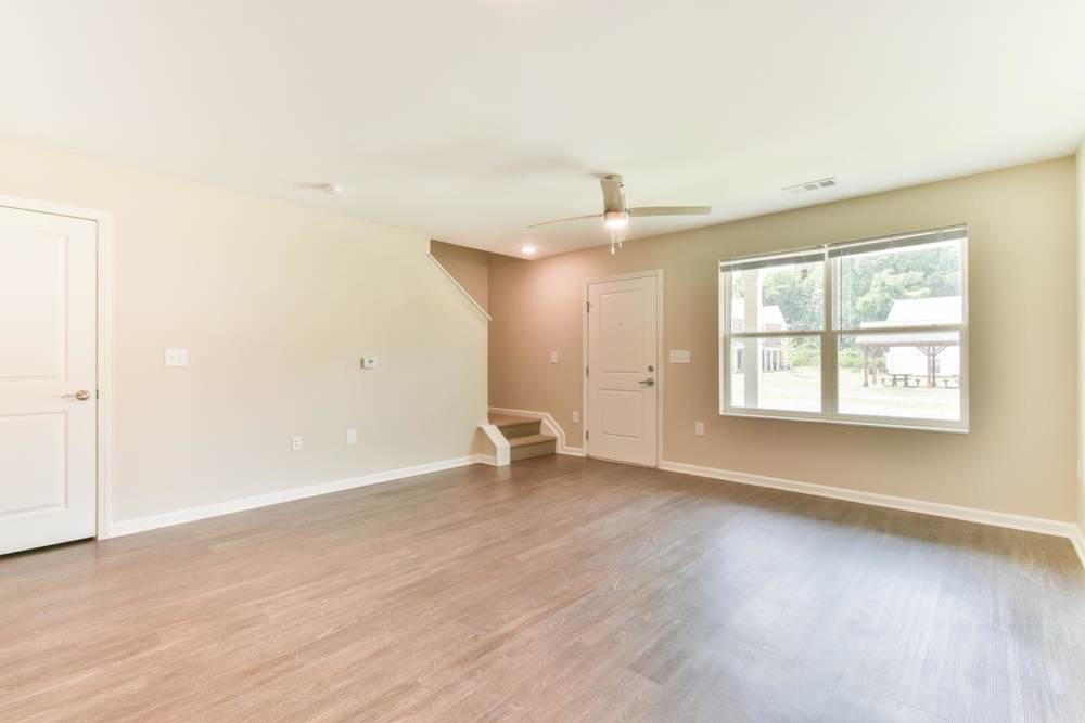 Spacious living room with wood flooring and large window at Canaan Crossing in Madison. GA