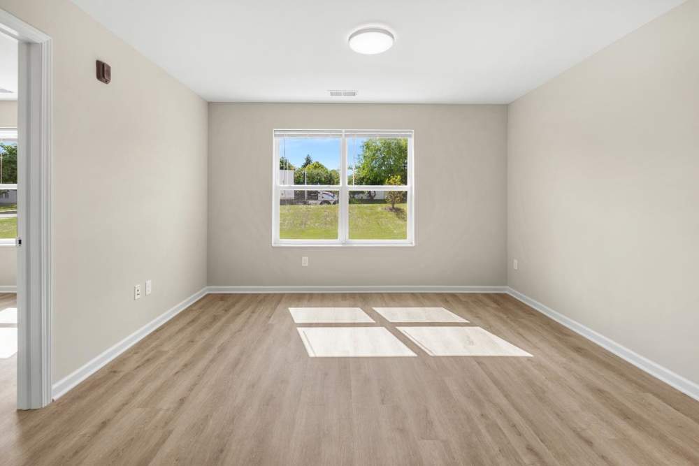 Well-lit living room with wood style flooring at Deville Manor in Oswego, Illinois