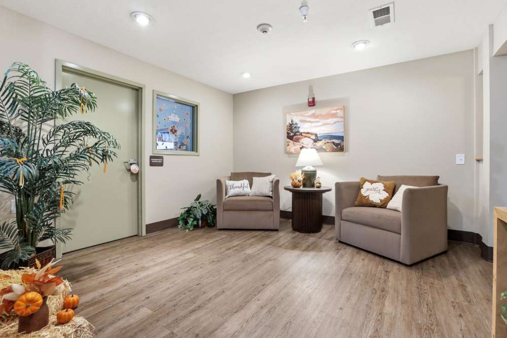 Welcoming lobby with wood-style flooring, comfortable seating, decorative plants, and seasonal decor at Norwood Greene Senior Living in Marietta, Ohio