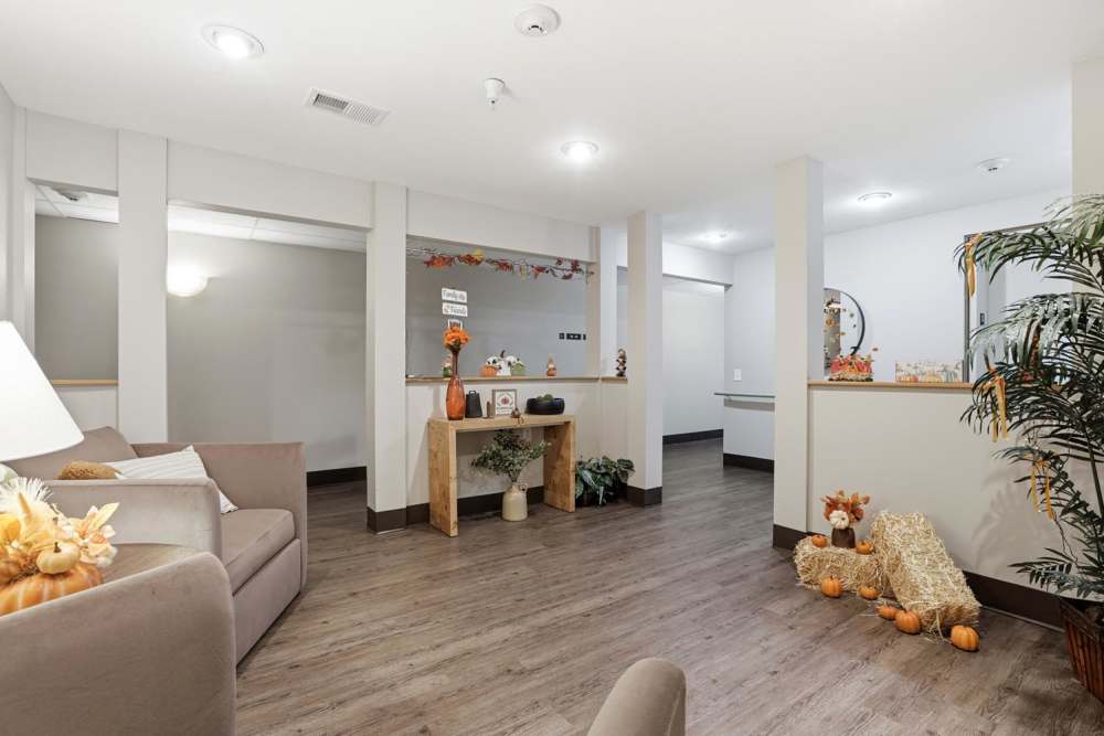 Welcoming lobby with wood-style flooring and seasonal decorations, cozy seating area and plants at Norwood Greene Senior Living in Marietta, Ohio