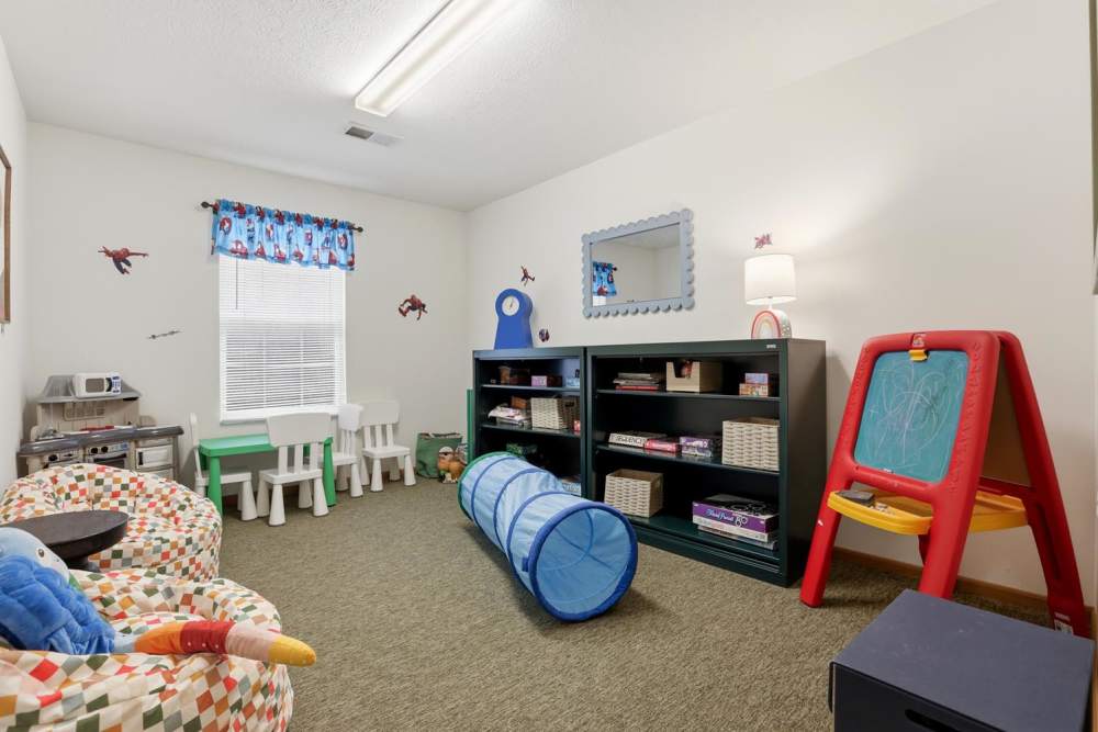Bright children's playroom with colorful rugs, small tables, and a play tunnel, fostering creativity and fun at Norwood Greene Senior Living in Marietta, Ohio