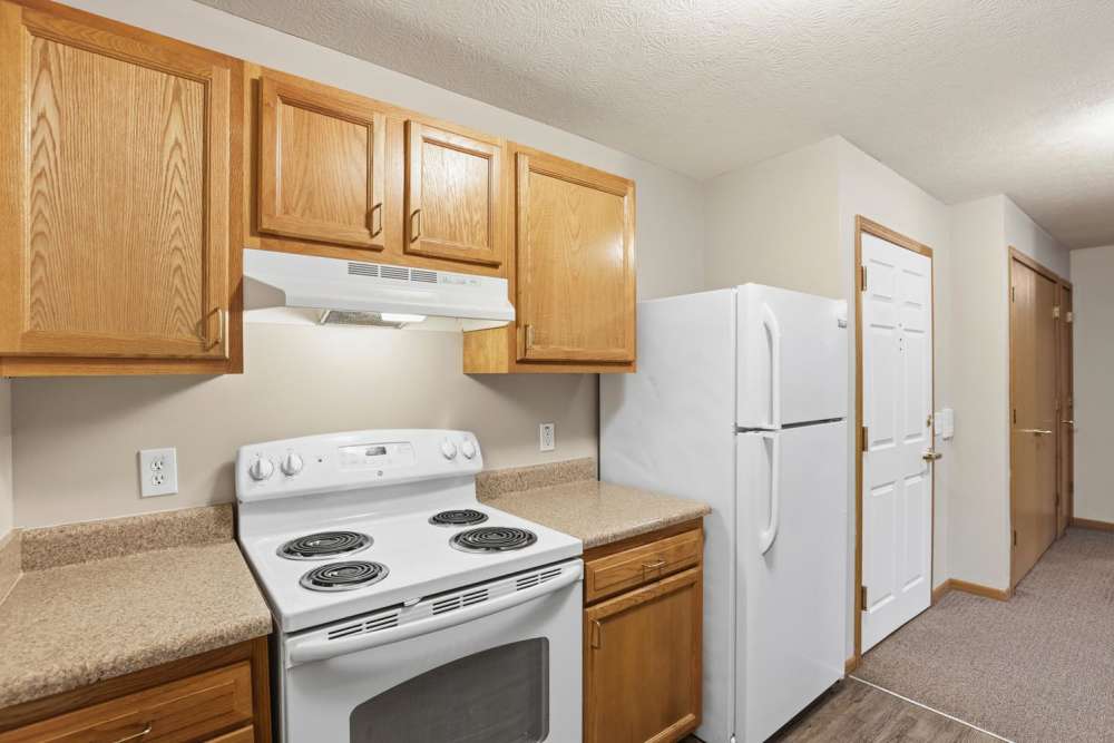 Kitchen featuring wooden cabinets, white appliances, and granite countertops with a spacious layout at Norwood Greene Senior Living in Marietta, Ohio